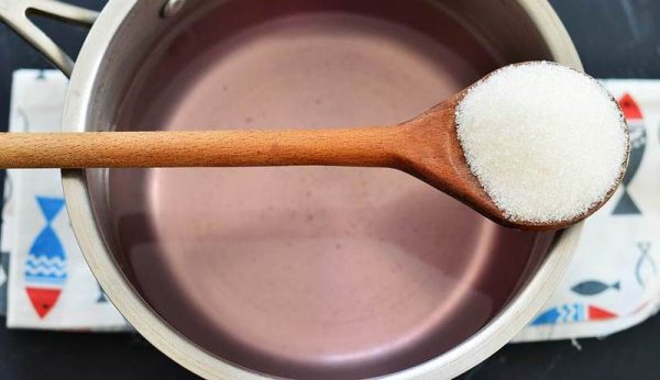 Заливка для компота из винограда в металлической кастрюле и деревянная ложка с сахаром