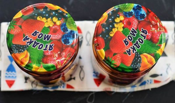 Банки с компотом под цветными металлическими крышками на столе