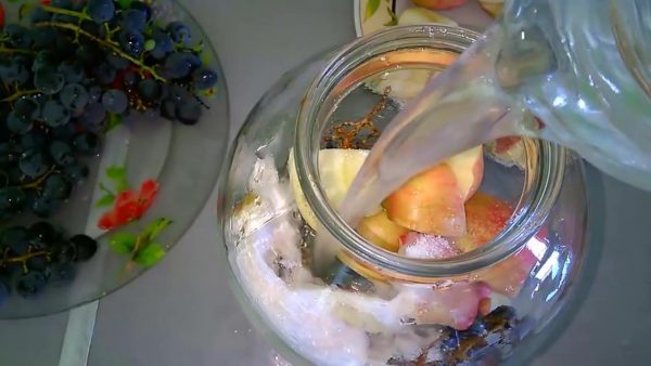 Заливка воды в банку с виноградом и яблоками
